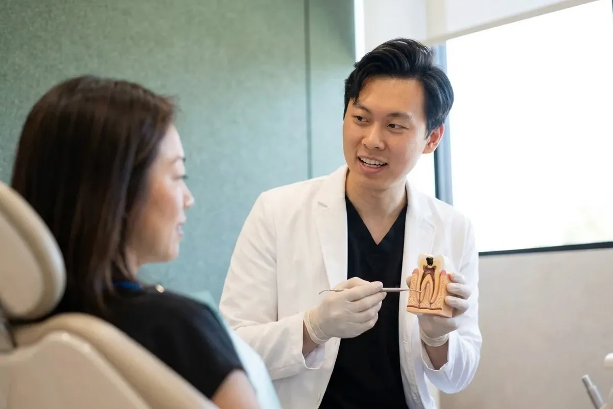 El Dr. Yiyang Zou le muestra a una paciente en un modelo dental cómo la caries daña un diente.